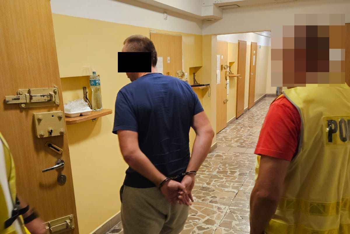 Zatrzymany mężczyzna z założonymi kajdankami na ręce trzymane z tyłu.