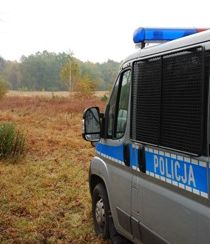 zdjęcie poglądowe przedstawiające policyjny radiowóz, który stoi nad brzegiem lasu