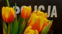 zdjecie przedstawia kwiaty na tle munduru policyjnego