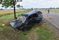 rozbity granatowy pojazd w rowie. W tle policjanci