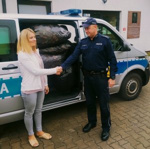 zdjęcie przedstawia policjantów pracowników hospicjum przy przekazaniu nakrętek