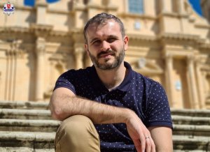 zdjęcie przedstawia mężczyznę w niebieskiej koszuli na jasnym tle