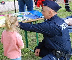 zdjęcie przedstawia dzielnicowego z dzieckiem