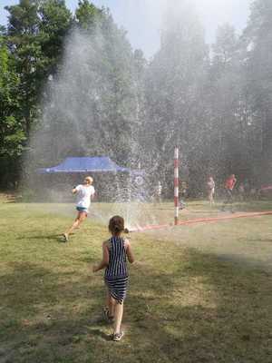 zdjęcie przedstawia dzieci bawiące się w kurtynie wodnej na festynie