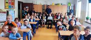 zdjęcie przedstawia dzielnicowego z dziećmi w klasie