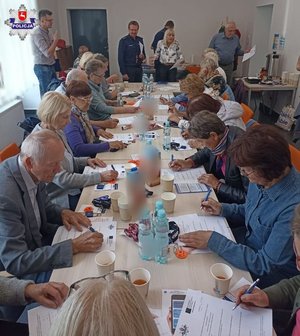 zdjęcie przedstawia seniorów siedzących przy stole
