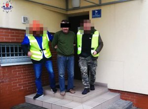 policjanci prowadzą mężczyznę, który znęcał się nad matka i groził funkcjonariuszowi