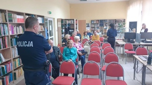 na zdjęciu policjanci przeprowadzający spotkanie z seniorami, którzy siedzą na krzesłach w Bibliotece Miejskiej w Lubartowie