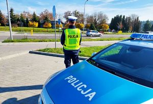 na zdjęciu policjant z radiowozem który patroluje rejon cmentarza