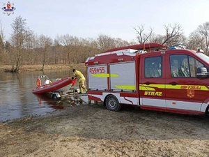 na zdjęciu łódz poszukiwawcza, policjant i strażacy