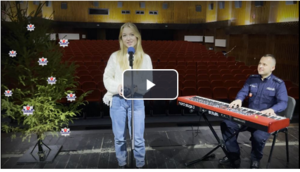 na zdjęciu policjant  i kobieta śpiewająca kolędę