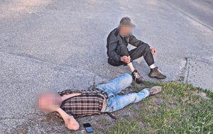 Zdjęcie przedstawia dwóch pijanych mężczyzn leżących na jezdni.