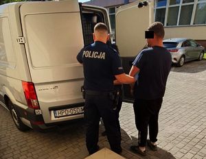 policjant prowadzi zatrzymanego do radiowozu