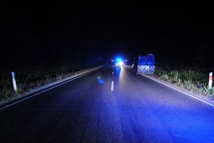 samochód typu bus stoi na poboczu jezdni, przed nim stoi samochód z włączonymi reflektorami .