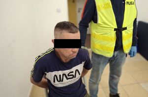 na zdjeciu siedzący zatrzymany i policjant