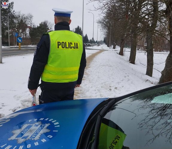 policjant stojacy przy radiowozie