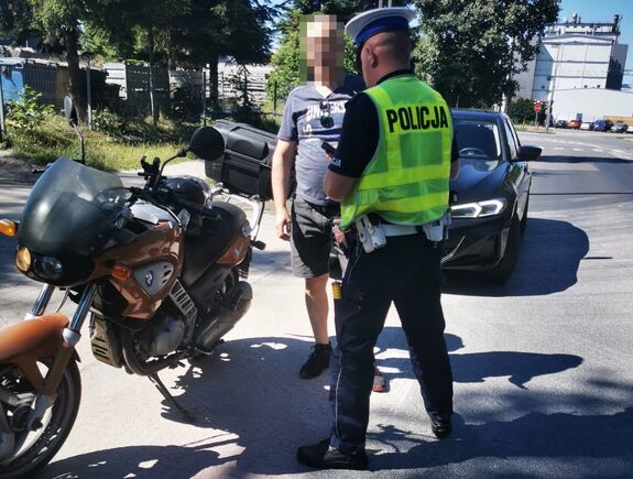 Policjant stoi obok kierującego motocyklem
