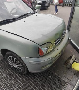 uszkodzone auto i drzwi sklepu