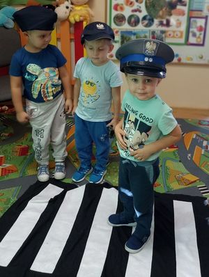 na pierwszym planie trzech chłopców wczapakach policjantaktórzy stojąobok siebie