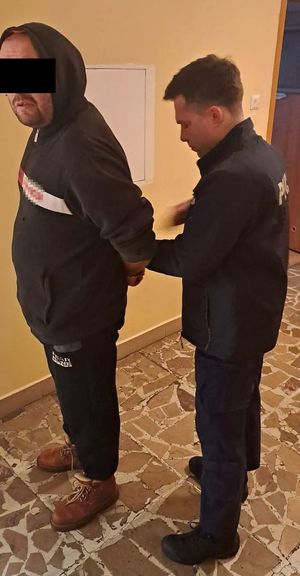 policjant zakłada kajdanki zatrzymanemu